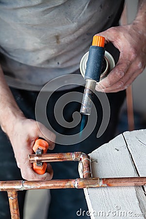 Closeup professional master plumber hands soldering copper pipes gas burner. Concept installation, plumbing replacement, solder Stock Photo