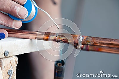 Closeup professional master plumber holding flux paste for soldering and brazing seams of copper pipe gas burner. Concept Stock Photo