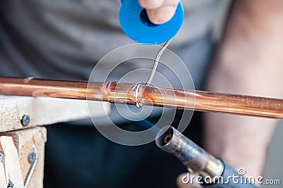 Closeup professional master plumber holding flux paste for soldering and brazing seams of copper pipe gas burner. Concept Stock Photo