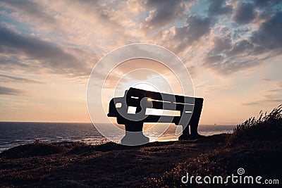 Closeup of a quiet bench on a sandy beach at sunset in Porthcawl Stock Photo