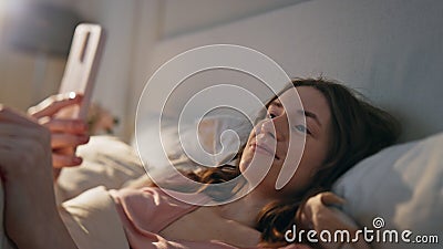 Closeup relaxed girl videocalling in bed. Positive awake woman holding mobile Stock Photo