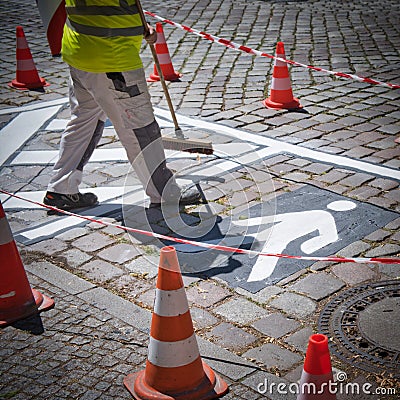 Closeup of road worker preparing a white pictogram at a street with orange cones for safety & x28;square& x29; Stock Photo