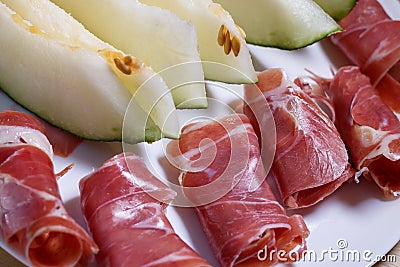 Closeup of rolled slices of cured pork ham jamon with melon Stock Photo