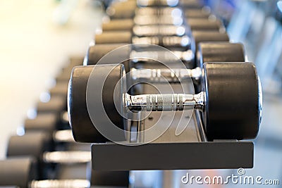 Closeup rows of metal dumbbells on rack in the gym Stock Photo