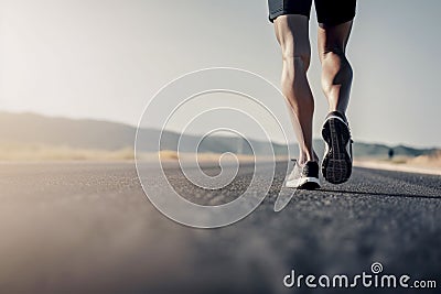 Closeup of runner shaved feet in running shoes going for a run on the road at sunrise or sunset. Stock Photo