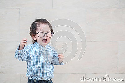 Closeup sad asian kid cry because he want something on marble stone wall textured background with copy space Stock Photo