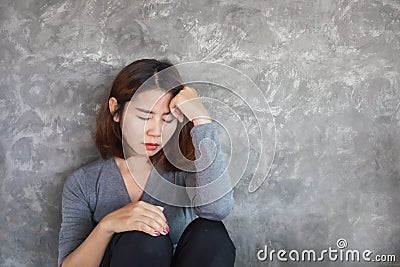 Sad Asian woman sitting alone against the wall feeling depressed and lonely Stock Photo