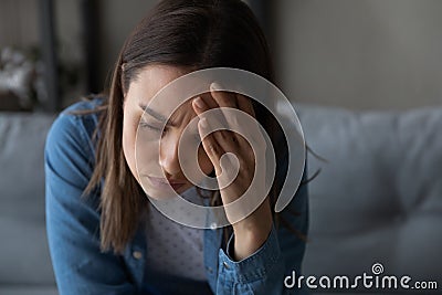 Closeup sad woman sit on sofa touch aching head Stock Photo