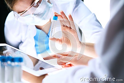 Closeup of scientific research team with clear solution in laboratory. Blonde female chemist holds test tube of glass Stock Photo