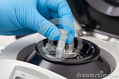 Closeup of a scientist hand placing a tube into an small table centrifuge. Spin column-based nucleic acid purification technique. Stock Photo