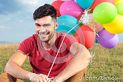 Closeup of seated casual man with balloons Stock Photo