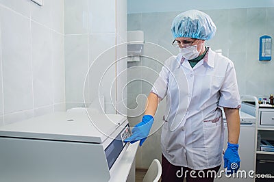 Closeup of a senior female chemist setting up some sample blood tubes inside a centrifuge for some test in a lab. Stock Photo