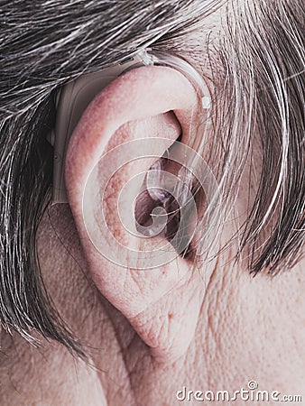 Closeup senior woman using hearing aid Stock Photo