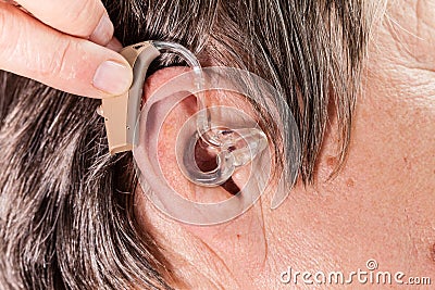 Closeup senior woman using hearing aid Stock Photo