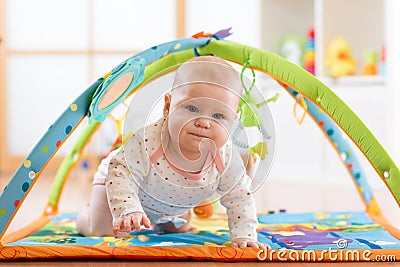 Closeup of seven months baby girl crawling on colorful playmat Stock Photo