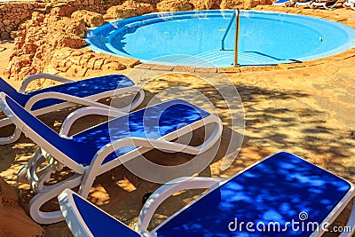Closeup several of sun loungers by a beautiful swimming pool. Stock Photo
