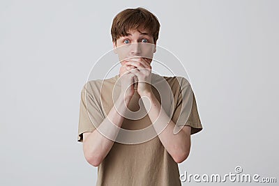 Closeup of shocked amazed young man student with blue eyes and short blond hair covered mouth by hands and looks directly in Stock Photo