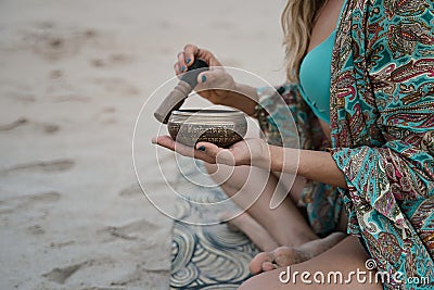 Closeup shot of an Arabic design metallic bowl in beautiful girl's hands in a swimsuit on the beach Stock Photo