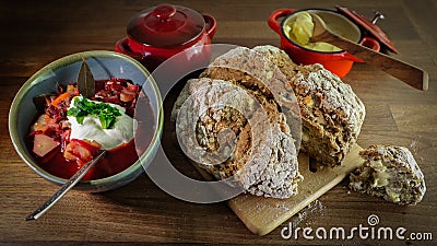 Closeup shot of banana bread on a board, red borscht, butter in a container, and a casserole Stock Photo