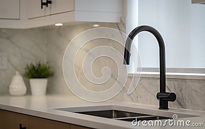 Closeup shot of a black faucet with a shite sink in a kitchen Stock Photo