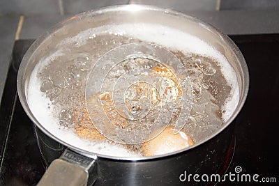 Closeup shot of boiling water with brown eggs on a stainless casserole Stock Photo