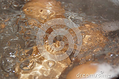 Closeup shot of boiling water with brown eggs on a stainless casserole Stock Photo