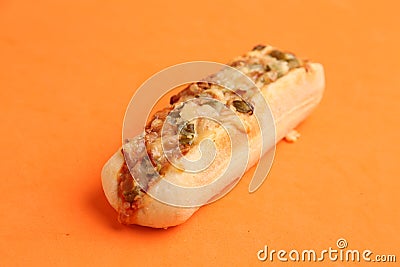 Closeup shot of a bread loaf with pizza toppings on an orange background Stock Photo