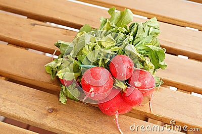 Closeup shot of a bundle of fresh red radish on a wooden surface Stock Photo