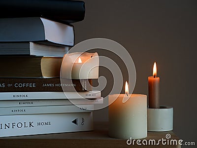 Closeup shot of candles and a stack of books on a wooden table Editorial Stock Photo