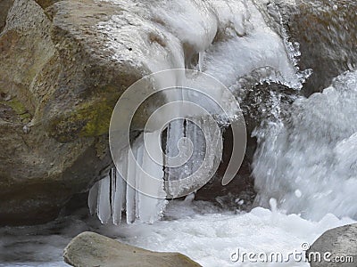 Closeup shot of a cascade of water with white ice melting on the rock Stock Photo