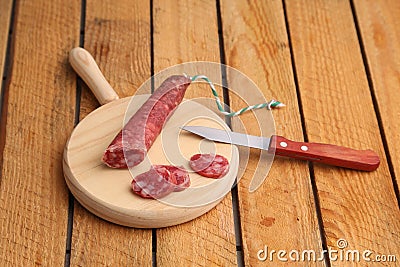Closeup shot of chopped chorizo sausage on a wooden board and a knife on a wooden table Stock Photo