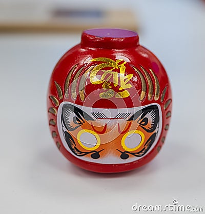 Closeup shot of Daruma or a red-painted good luck doll on a white table Stock Photo