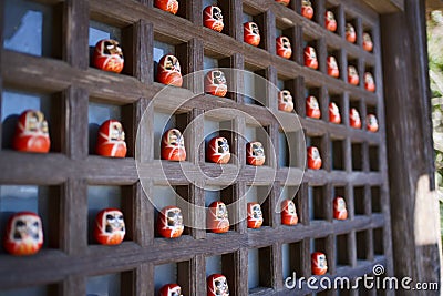 Closeup shot of Darumas or red-painted good luck dolls on small shelves Stock Photo