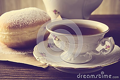 Closeup shot of donut with cup of tea on table in old-fashioned Stock Photo