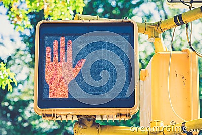 Closeup shot of an electric crosswalk sign with red hand signalling to stop walking Stock Photo