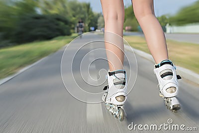 Closeup shot of female roller skates while rollerblading on blurred background of road Stock Photo