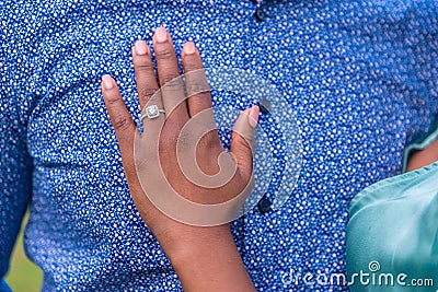 Closeup shot of a female's hand with an engagement ring on her fiance's chest Stock Photo