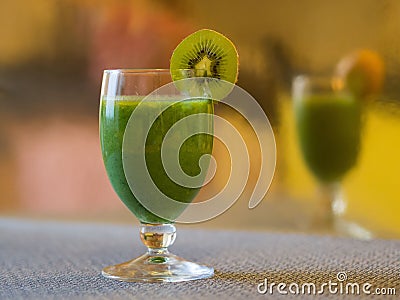 Closeup shot of a glass of kiwi smoothie decorated with a kiwi slice with a blur mirrored background Stock Photo