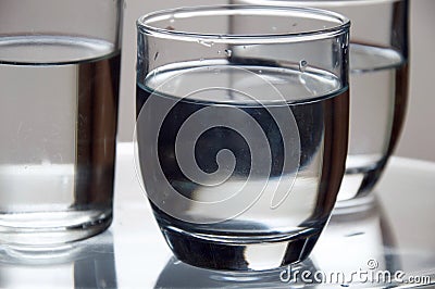Closeup shot of glasses of cold water on a transparent surface Stock Photo