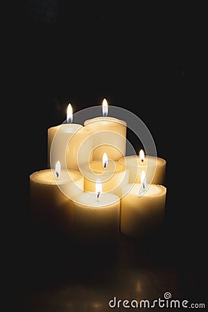 Closeup shot of a group of seven burning candles with black background Stock Photo