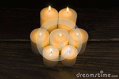 Closeup shot of a group of seven burning candles with black background Stock Photo