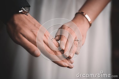 Closeup shot of the hands of newly married groom and the bride holding hands and wearing rings Stock Photo