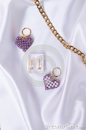 Closeup shot of heart shaped beaded keychains with a pair of earrings and a gold chain Stock Photo