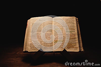 Closeup shot of a historic old Bible open on the Proverbs pages on display in a dark room Editorial Stock Photo