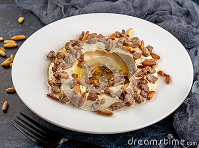 Closeup shot of Hummus with pieces of meat on a white plate, cold appetizer Stock Photo