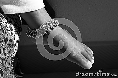 Closeup shot of Indian girl child ankle bracelet isolated on bare feet Stock Photo