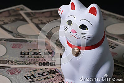 Closeup shot of a Japanese lucky cat (Maneki-neko) on Japanese 10000 banknotes Stock Photo