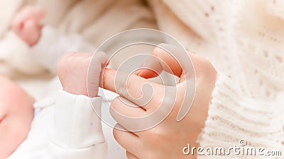 Closeup shot of little newborn baby hand holding big finger of young mother Stock Photo