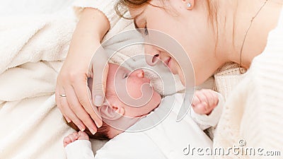 Closeup shot of little newborn baby lying next to mother and crying. Happy smiling woman looking at her little child Stock Photo