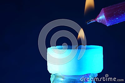 Closeup shot of a long candle lighting a small candle on a dark background Stock Photo